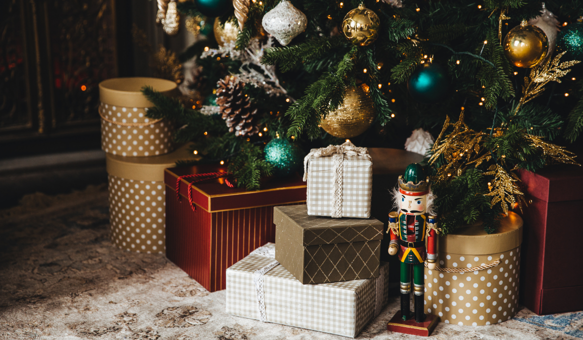 Various presents and a toy soldier lay on the floor beneath a decorated Christmas tree. 